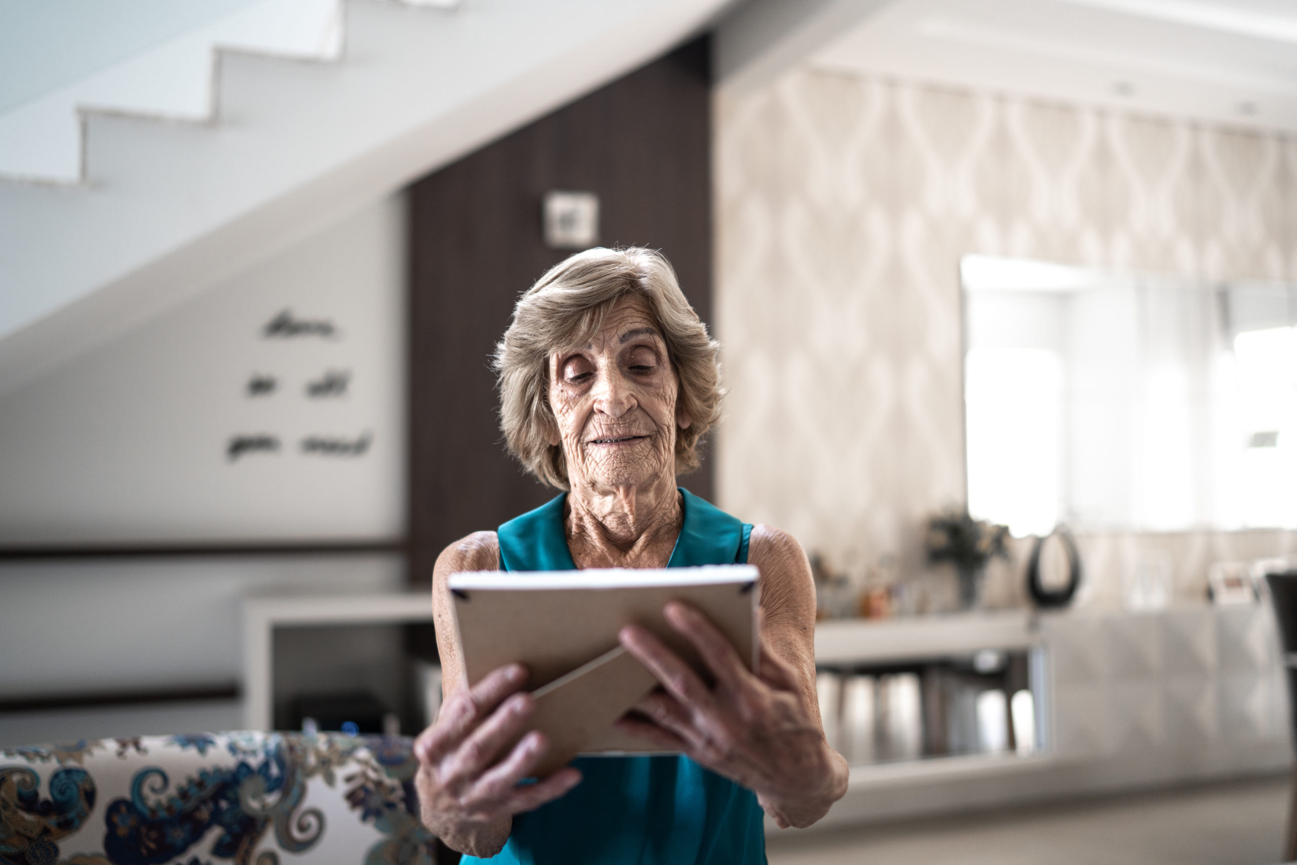 Sad senior woman looking at a photo frame at home