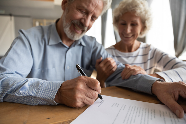 Close up satisfied older couple signing documents