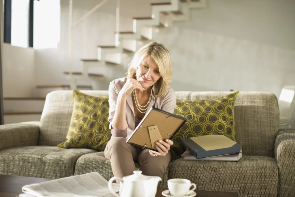 Woman looking at a photo frame at home