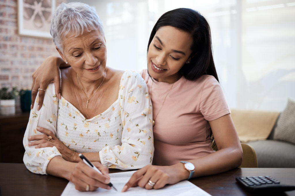 A young woman going over paperwork with her elderly mother at home